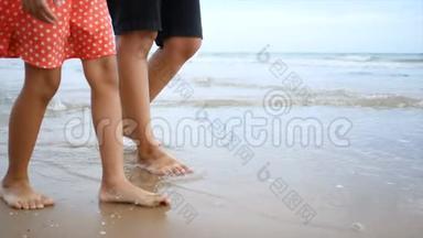 慢动作亚洲小女孩和妈妈一起在沙滩上与自然海浪海岸散步，为暑假提供概念